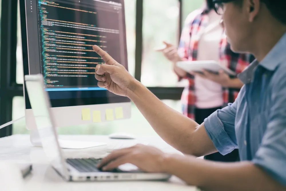 Developer pointing at code on a computer screen